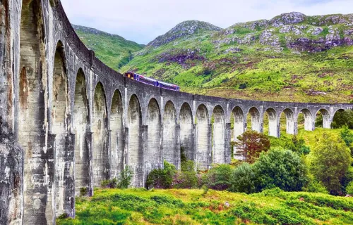 Train moving across the Glenfinnan viaduct in the Scottish Highlands