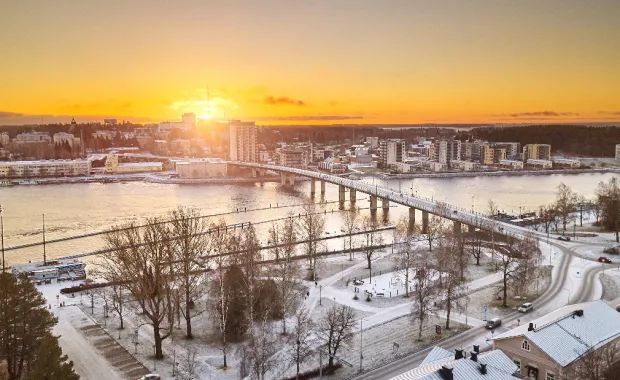 Aerial view of Joensuu, Finland covered in snow with the sun rising in the horizon. 